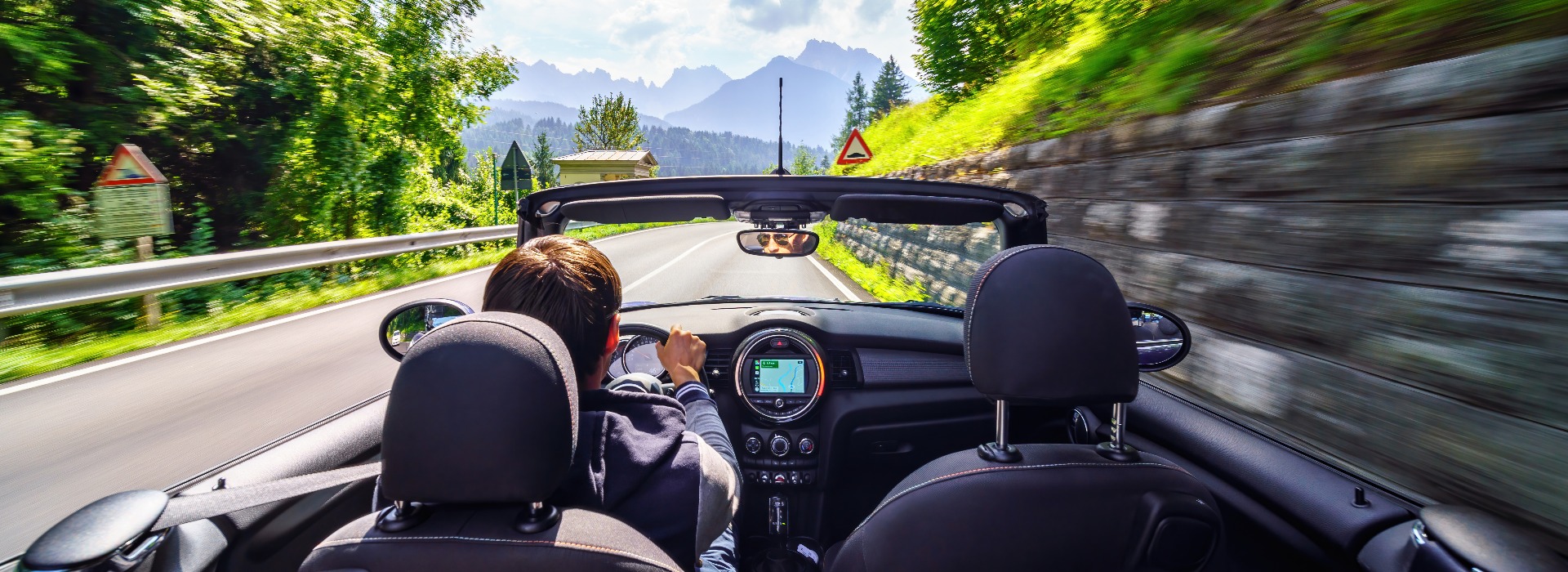 Driver's hands on a steering wheel of a convertible car. Road trip on the Italians road.